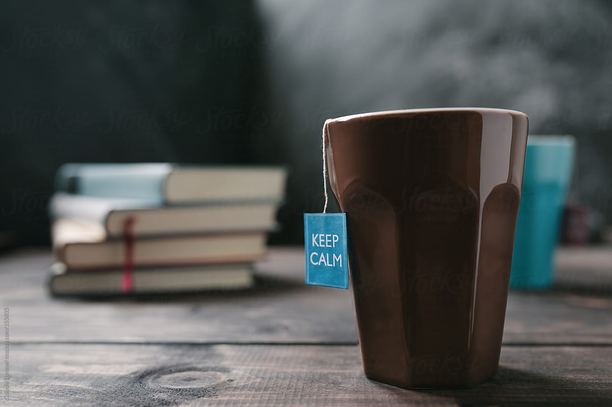 Mug, Tea Tag saying 'Keep Calm'  and a Stack of  Books on a Wooden Table