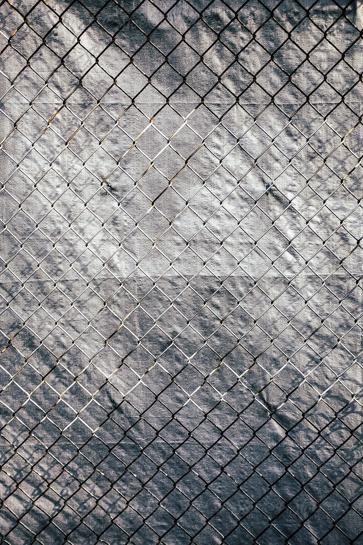 Chainlink fence in front of silver tarp