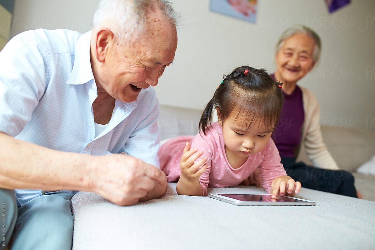 little asian girl using tablet indoor with her great grandparents