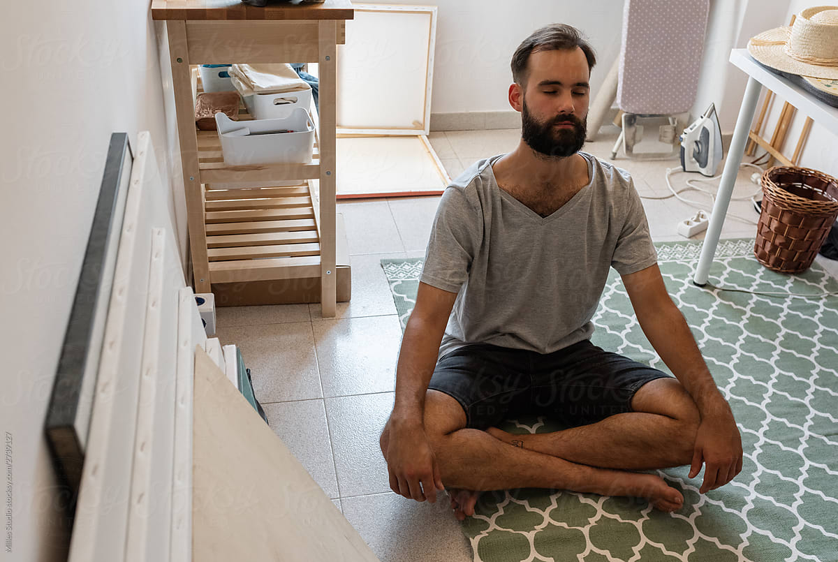 Adult man doing yoga meditation at home