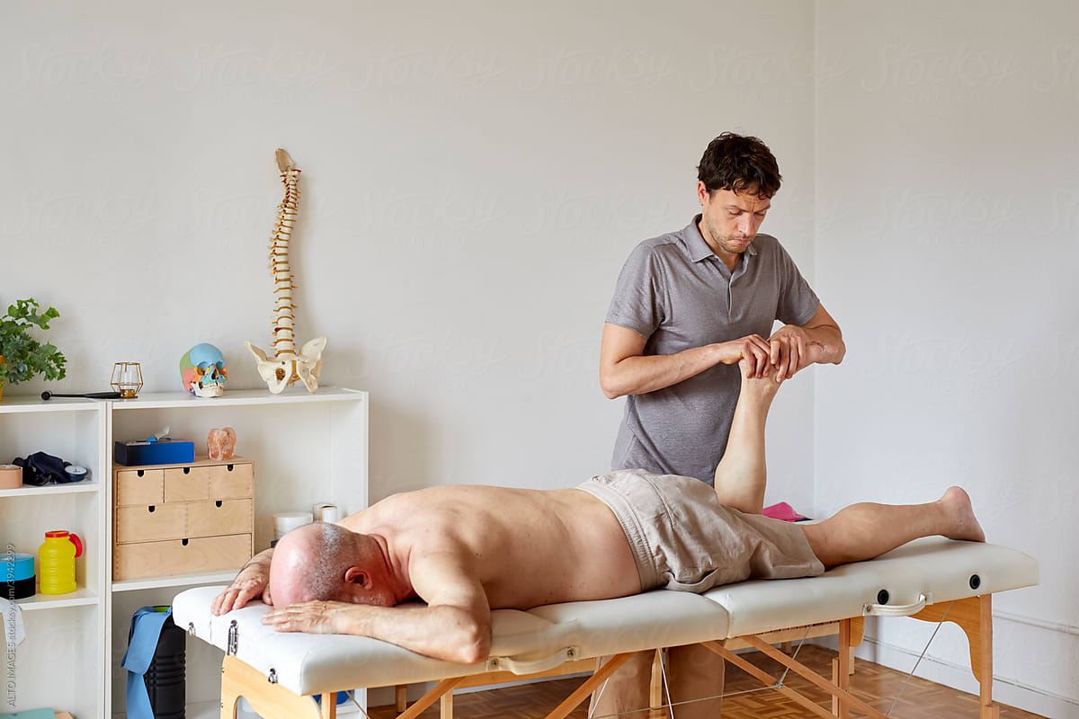 An osteopath holding patient\'s foot
