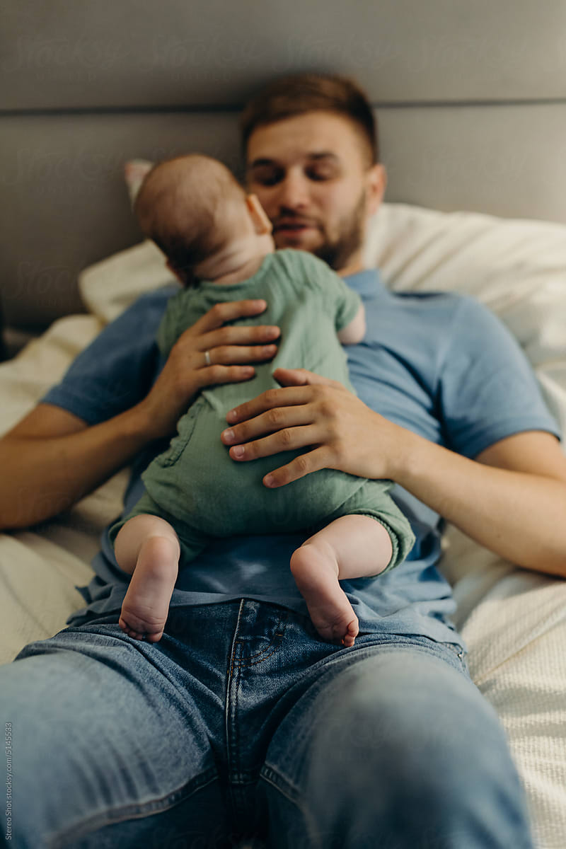 Man hugging baby on bed