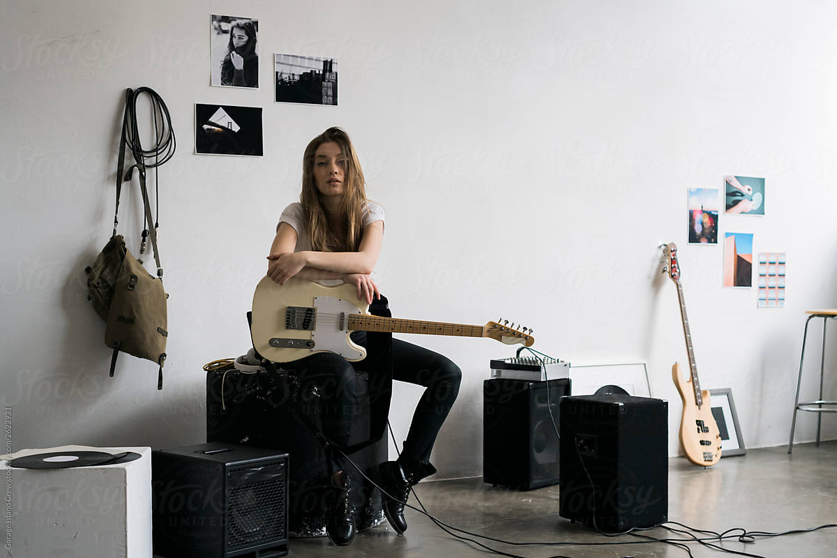 Cool young woman with guitar in rehearsal room