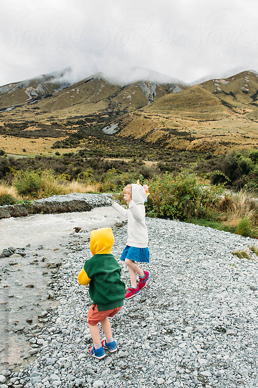 Two children throwing rocks in a mountain stream