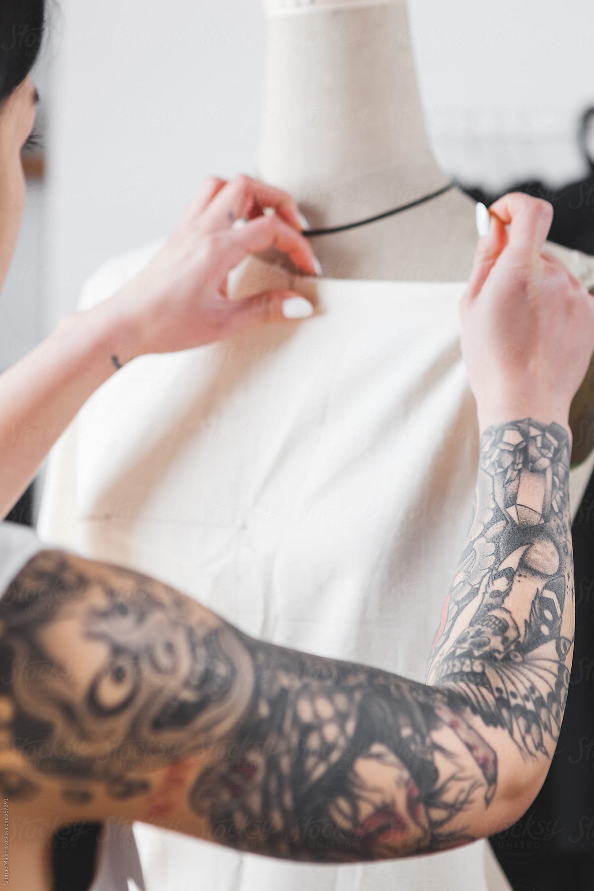 Young Fashion Designer with Tattooed Arm Working on a Mannequin