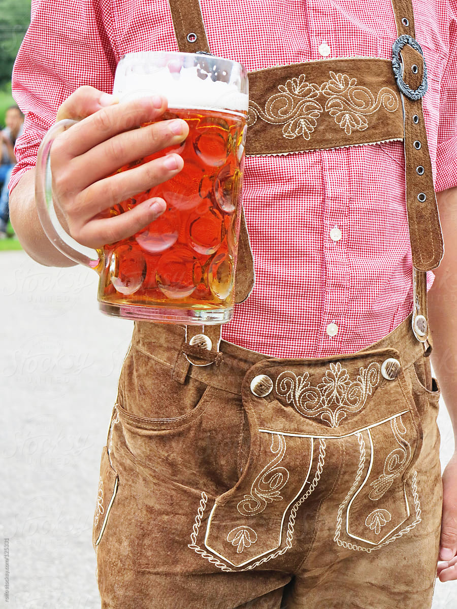 Man holding a glass of beer wearing German Bavarian clothes