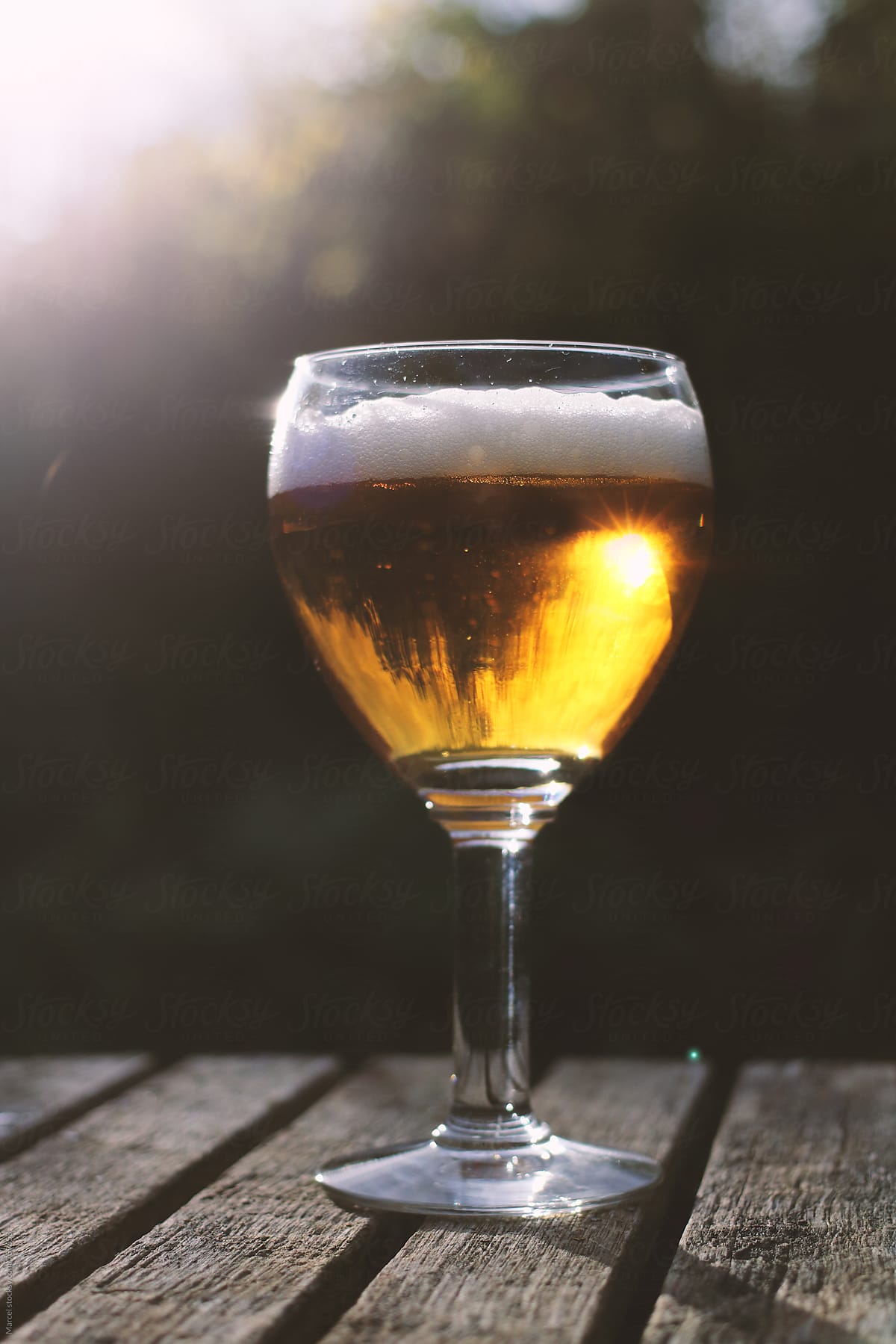 Big glass of beer on a garden table during the sunset