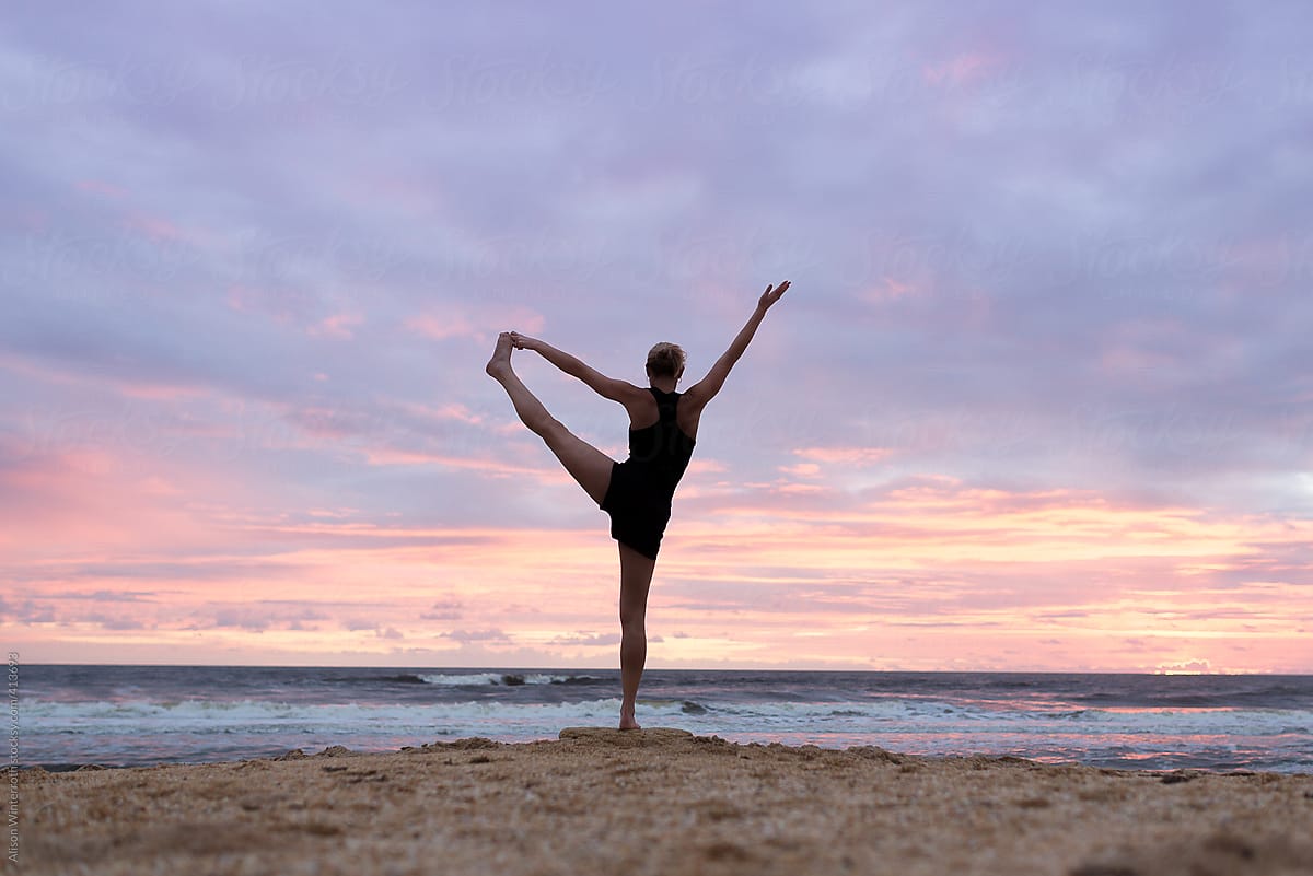 Woman Doing Yoga On The Beach At Sunrise