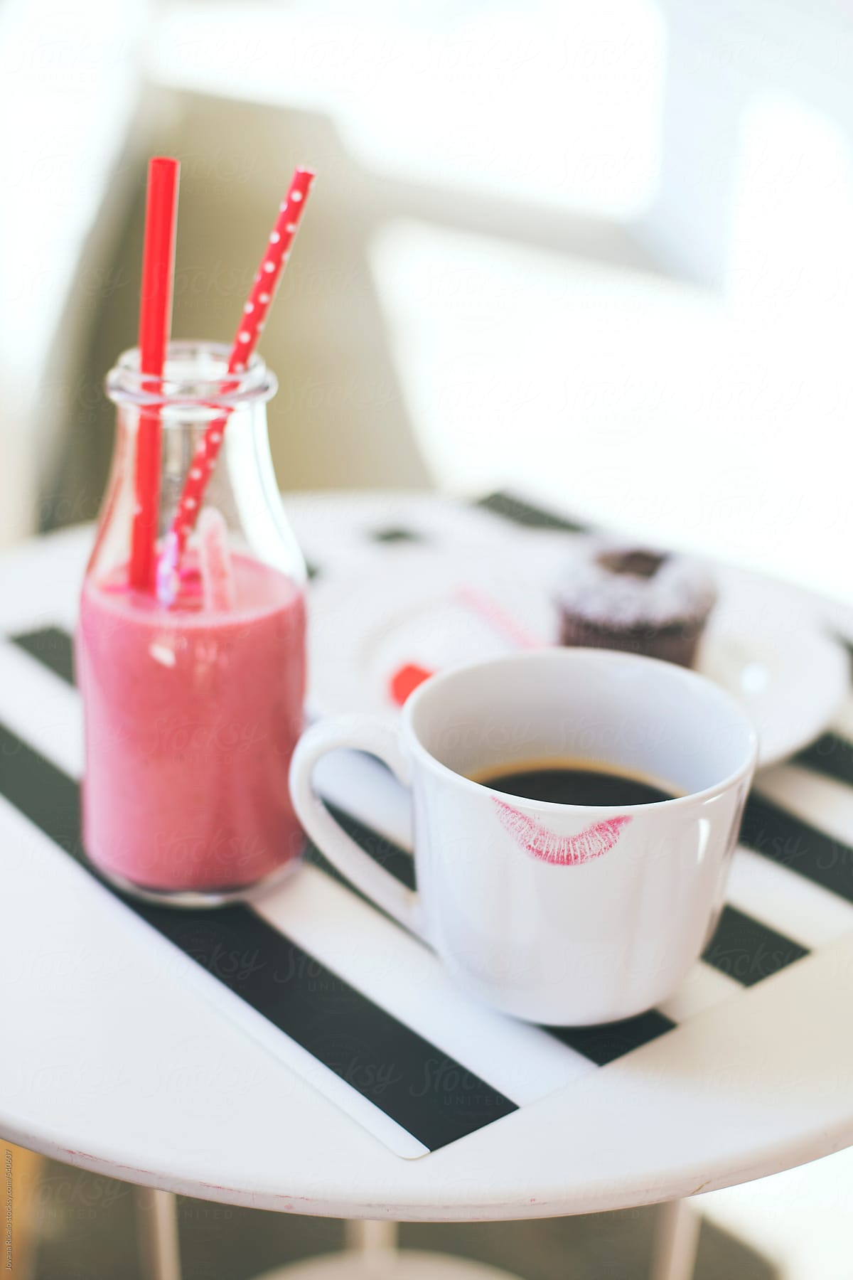 Coffee cup with lipstick print and strawberry smoothie drink on a white table
