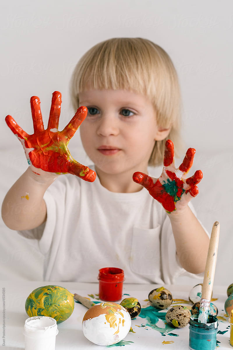 Boy in the process of coloring eggs stained his hands in paint
