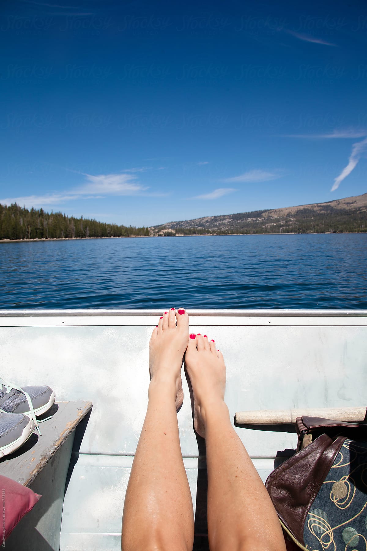 Woman\'s legs inside a metal fishing boat on a lake with a view