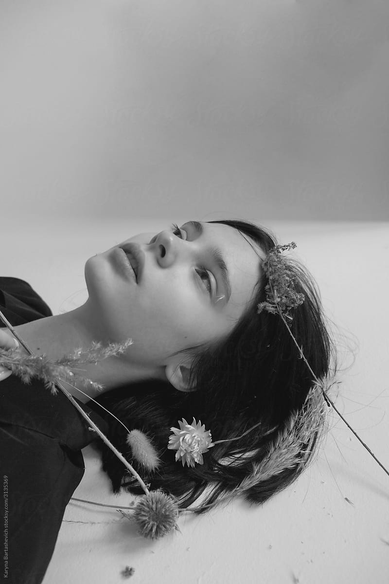 black and white portrait of a young girl in the studio lying on the floor with flowers in her hair