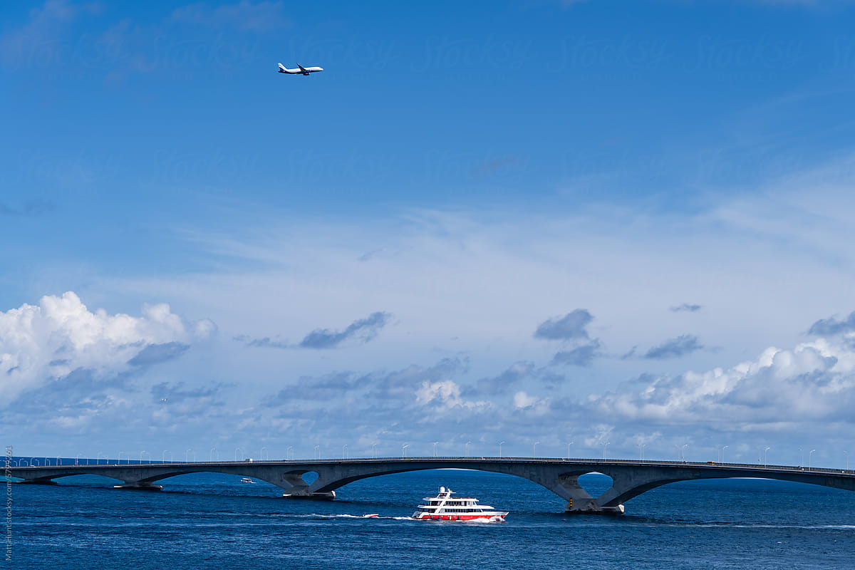 An airplane passes over a ferry boat in the Indian Ocean near Malé