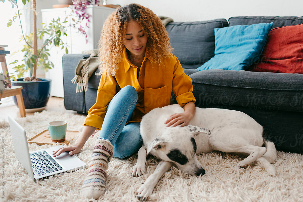 Teenager with computer and dog at home living room