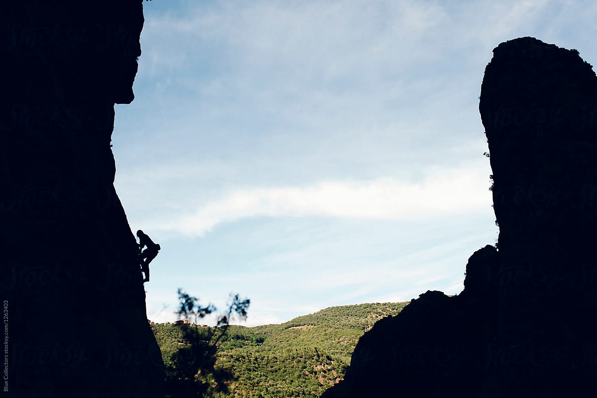 Alpinist silhouette climbing a rock wall