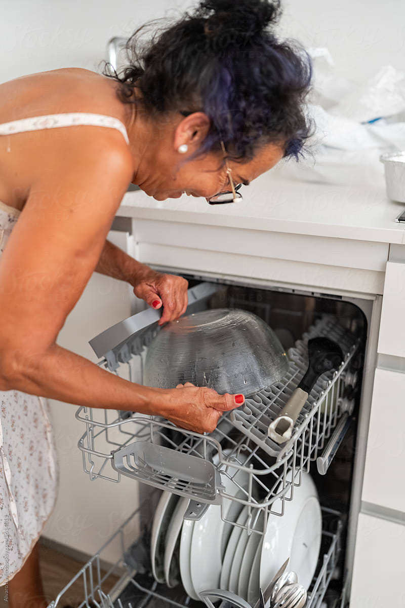Mature woman using dishwasher.