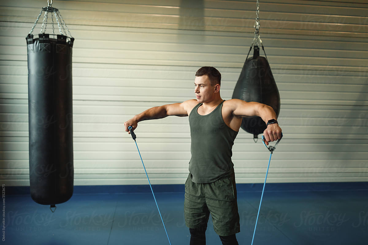 Boxer using sport equipment to stretching up muscles of upper body