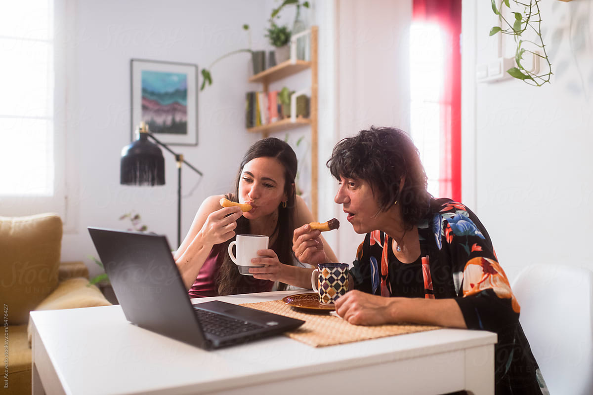 Mother and daughter having breakfast watching series on laptop