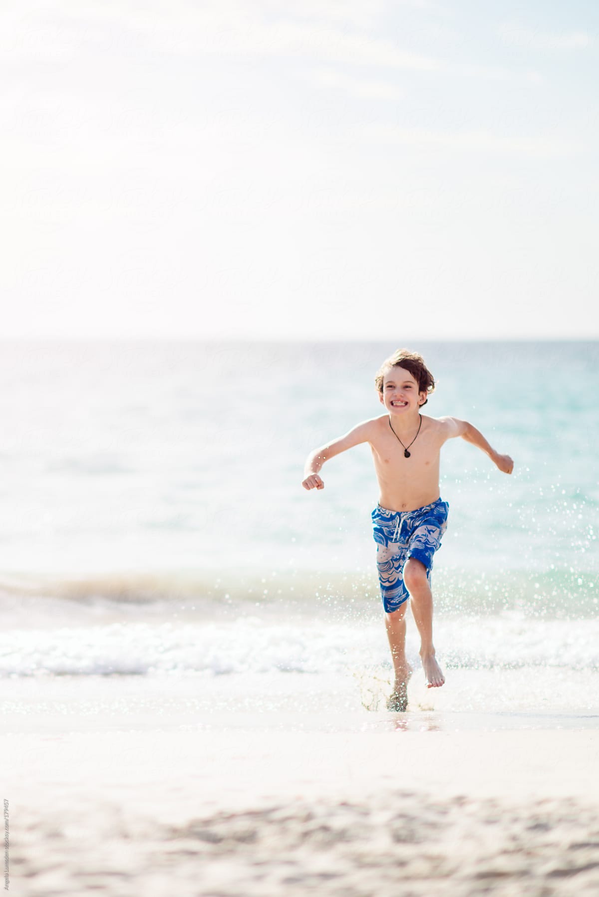 Boy in bathing suit running away from a small wave