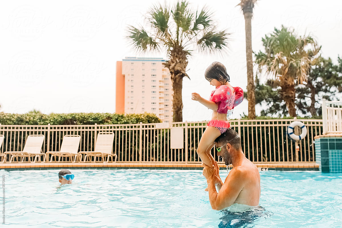 Father and daughter playing games in the pool.