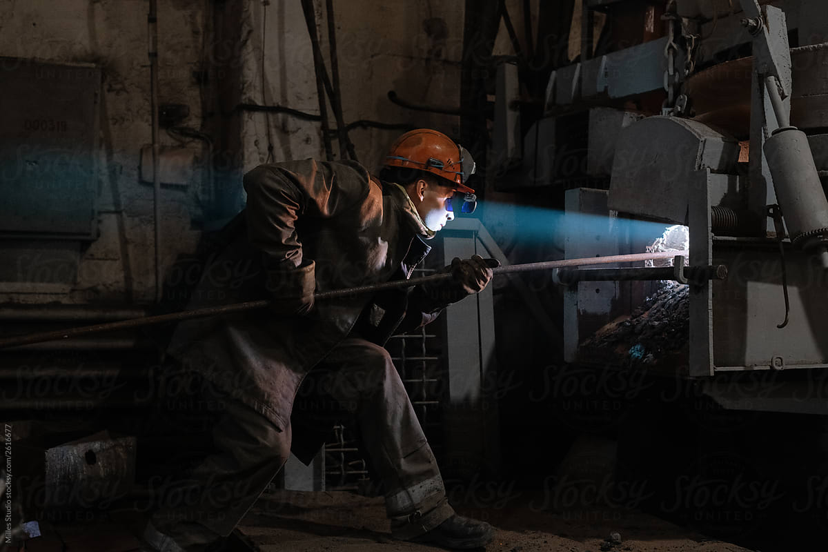 Factory worker putting bar inside furnace