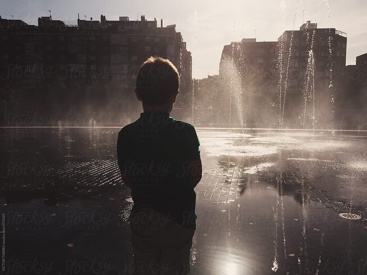 Boy Standing in front of a Fountain at Sunset