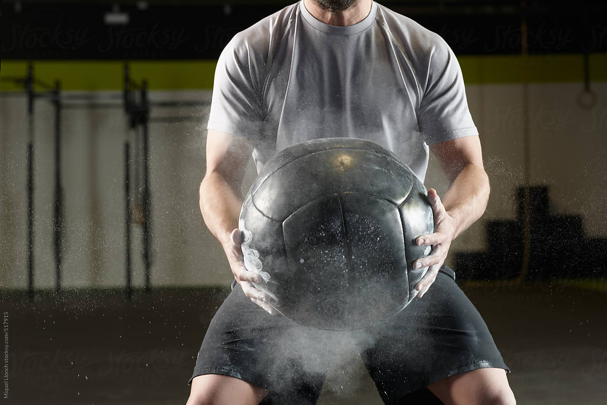 Fit man holding a weight ball in a  gym