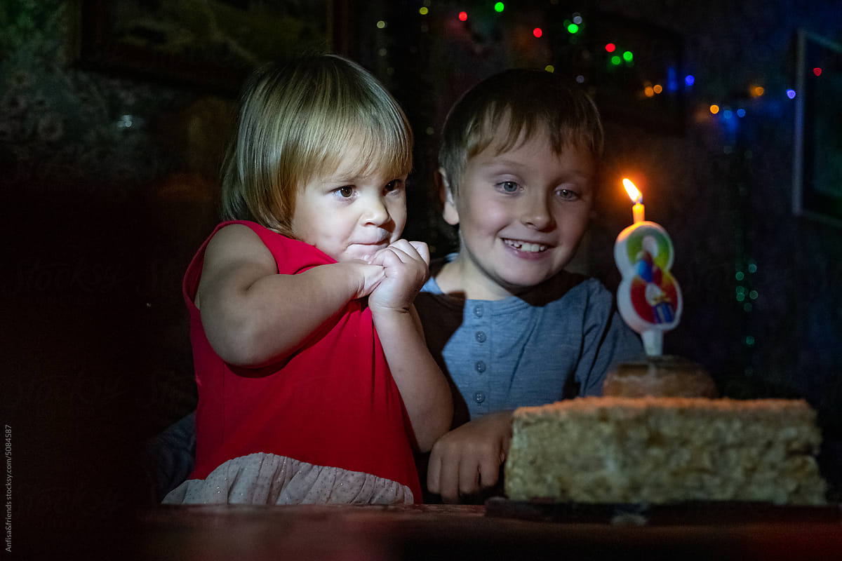 sincere kids looks at the candle on birthday cake
