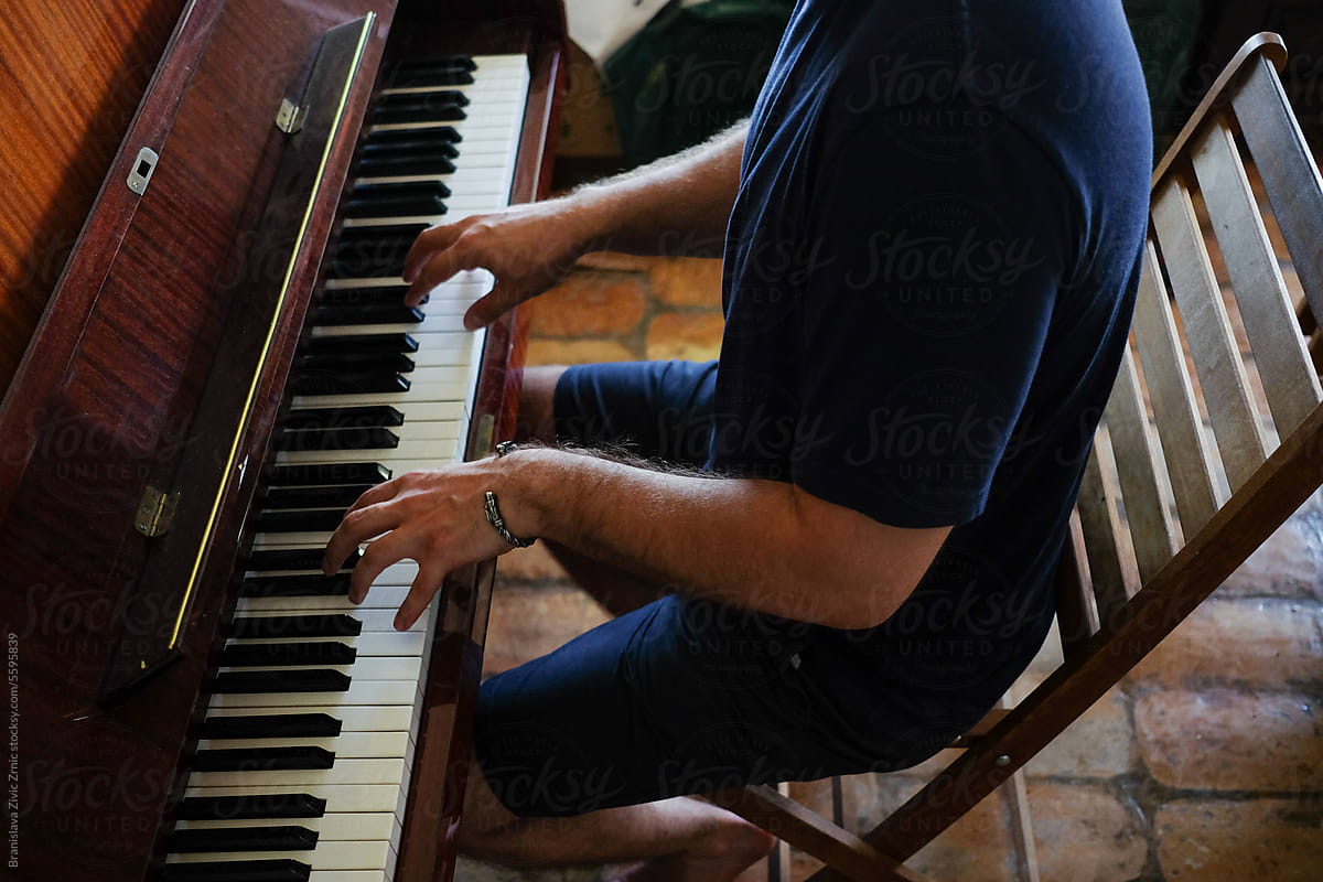 An Anonymous Man Enjoying Playing The Piano At Her Home