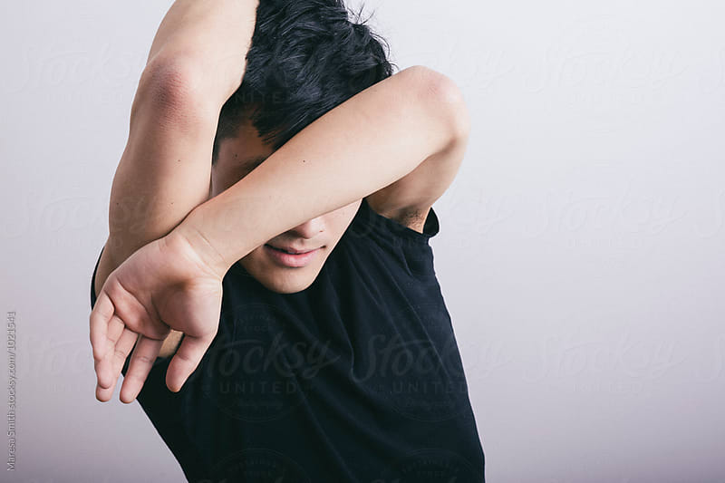A male dancer hiding his face with his arm, stretching and warming up
