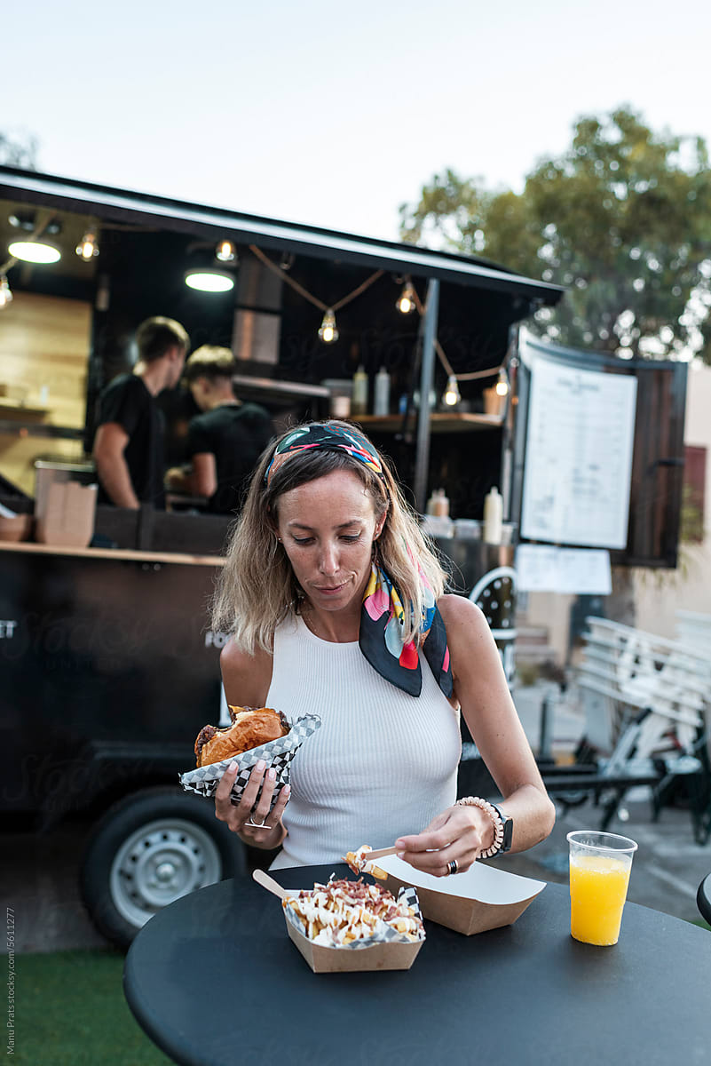 Client eating cheese burger and french fries in a food truck