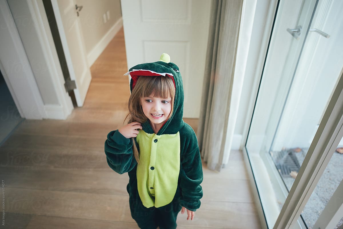Portrait of Cute little girl wandering around in dinosaur costume in family home
