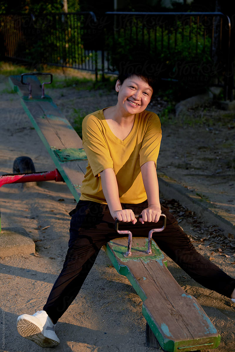Asian women playing on the seesaw, in the play area on the side of the community