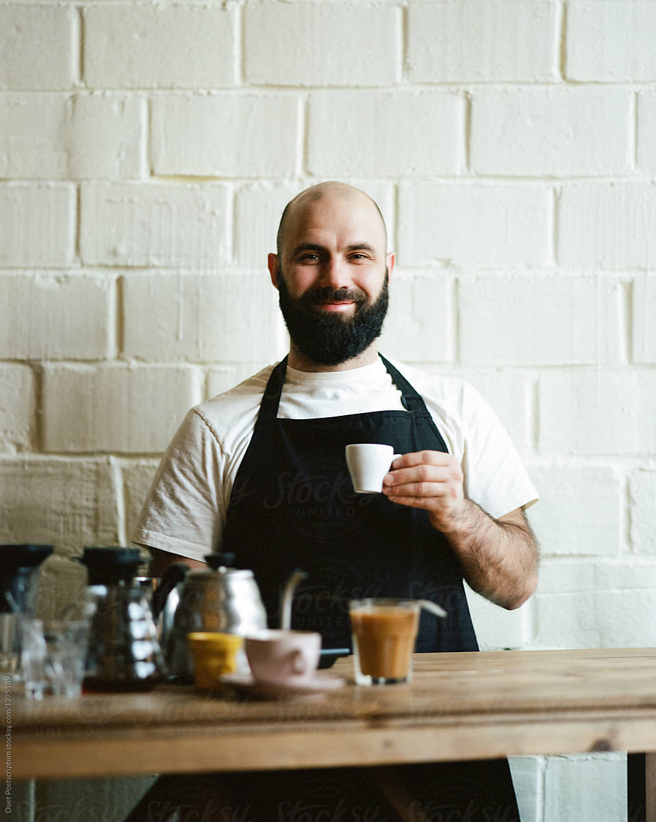 Bearded barista with cup of coffee