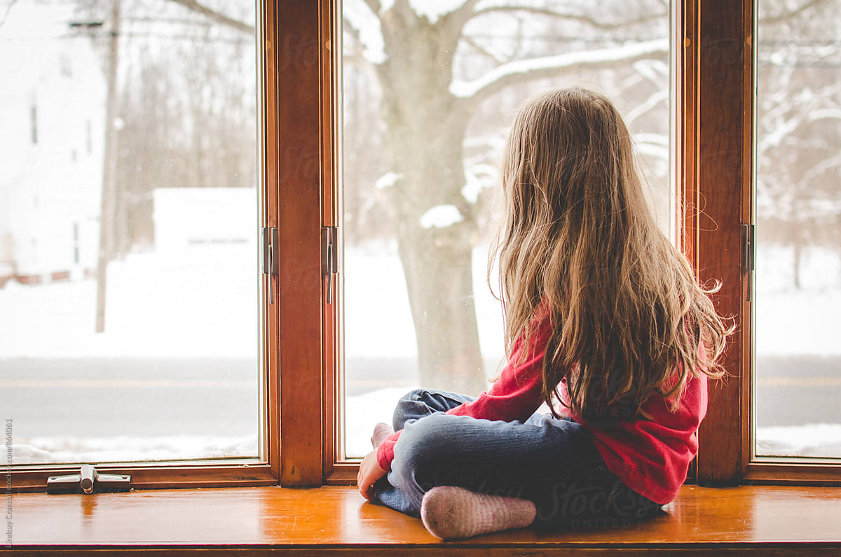 Girl sitting beside a snowy window