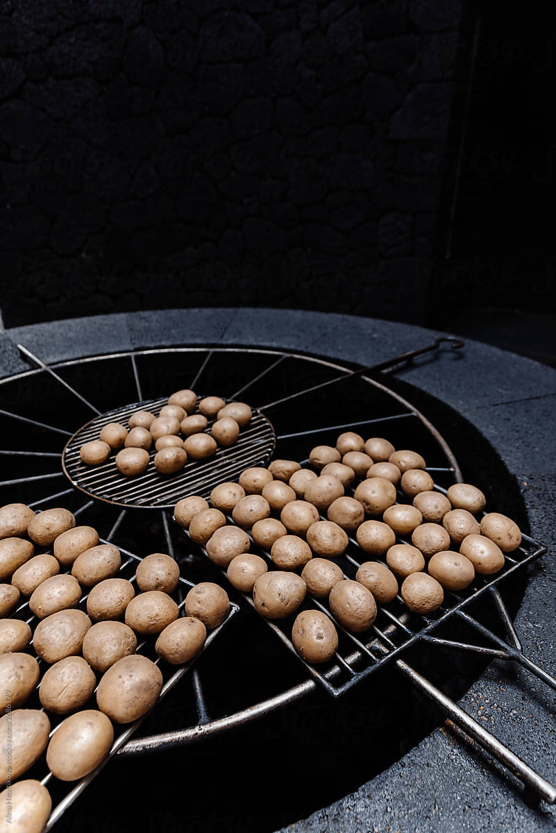 Fry potatoes on grilled grid in darkness cooking.