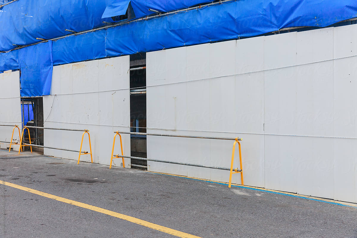Construction site covered with temporary walls and blue screens.