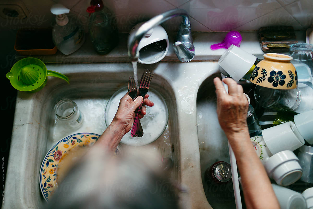 Woman\'s hands doing dishes on doble sink from above