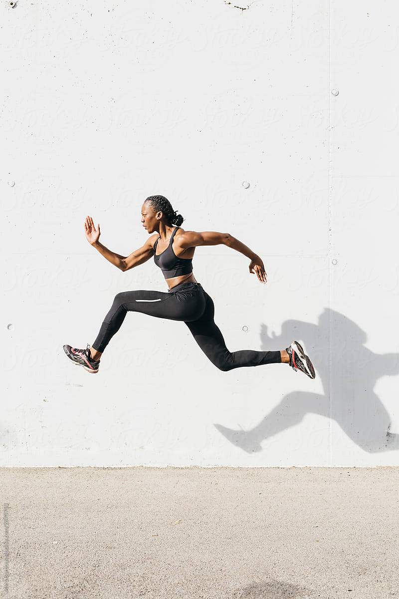 Young woman jumping in front of white wall