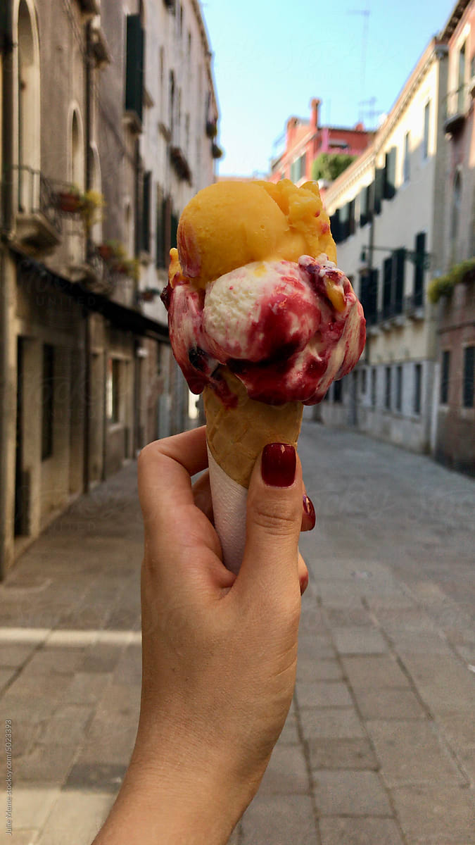 UGC, a hand holding an Italian gelato in the middle of the street