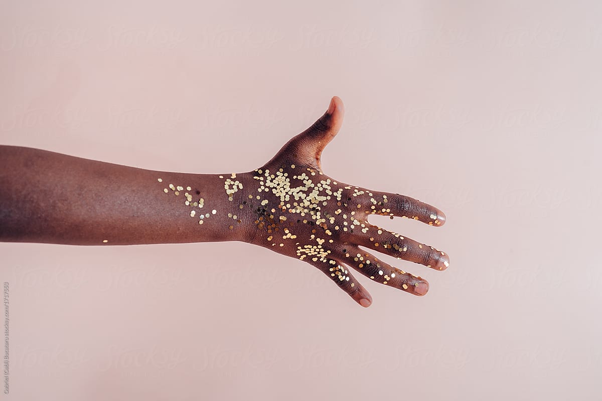Black girl\'s hand with golden confetti
