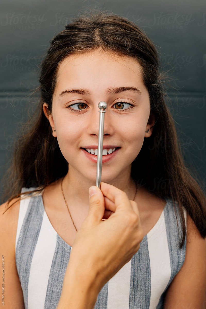 Happy young preteen girl looking at object in ophthalmology clinic