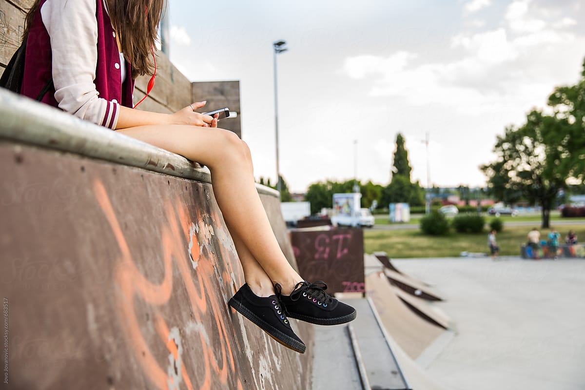 Ver Woman Checking Her Phone Sitting In A Skate Park Del Colaborador