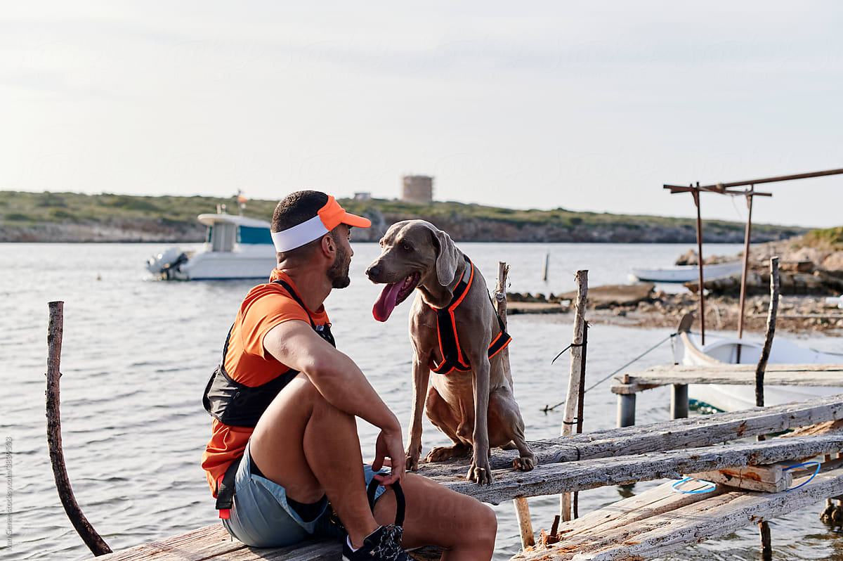 Man sitting with his dog on a jetty