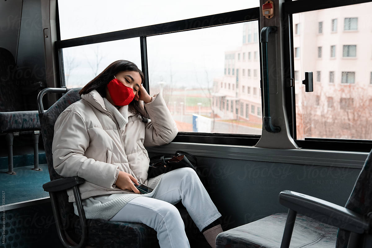Asian woman in mask sleeping in bus