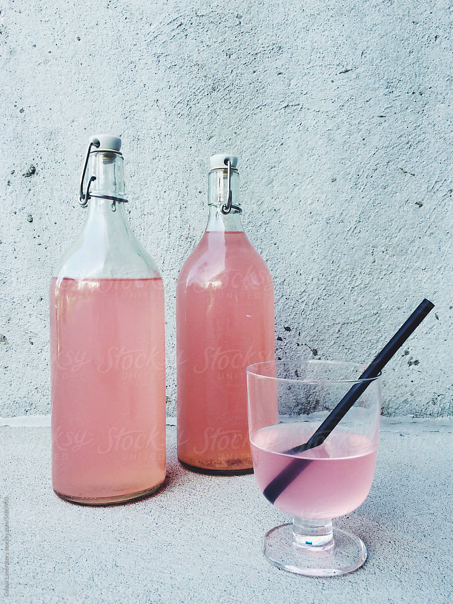 Glass bottles and a drinking glass filled with bright pink juice
