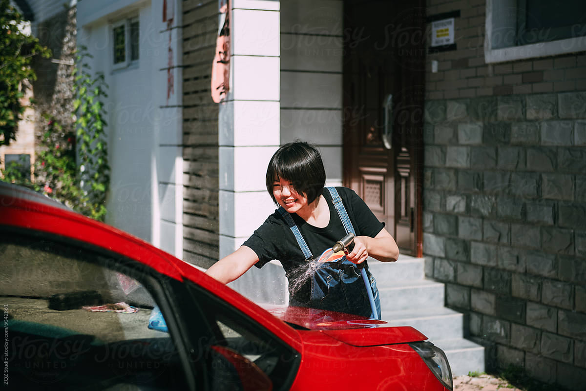 Young woman washing a red car