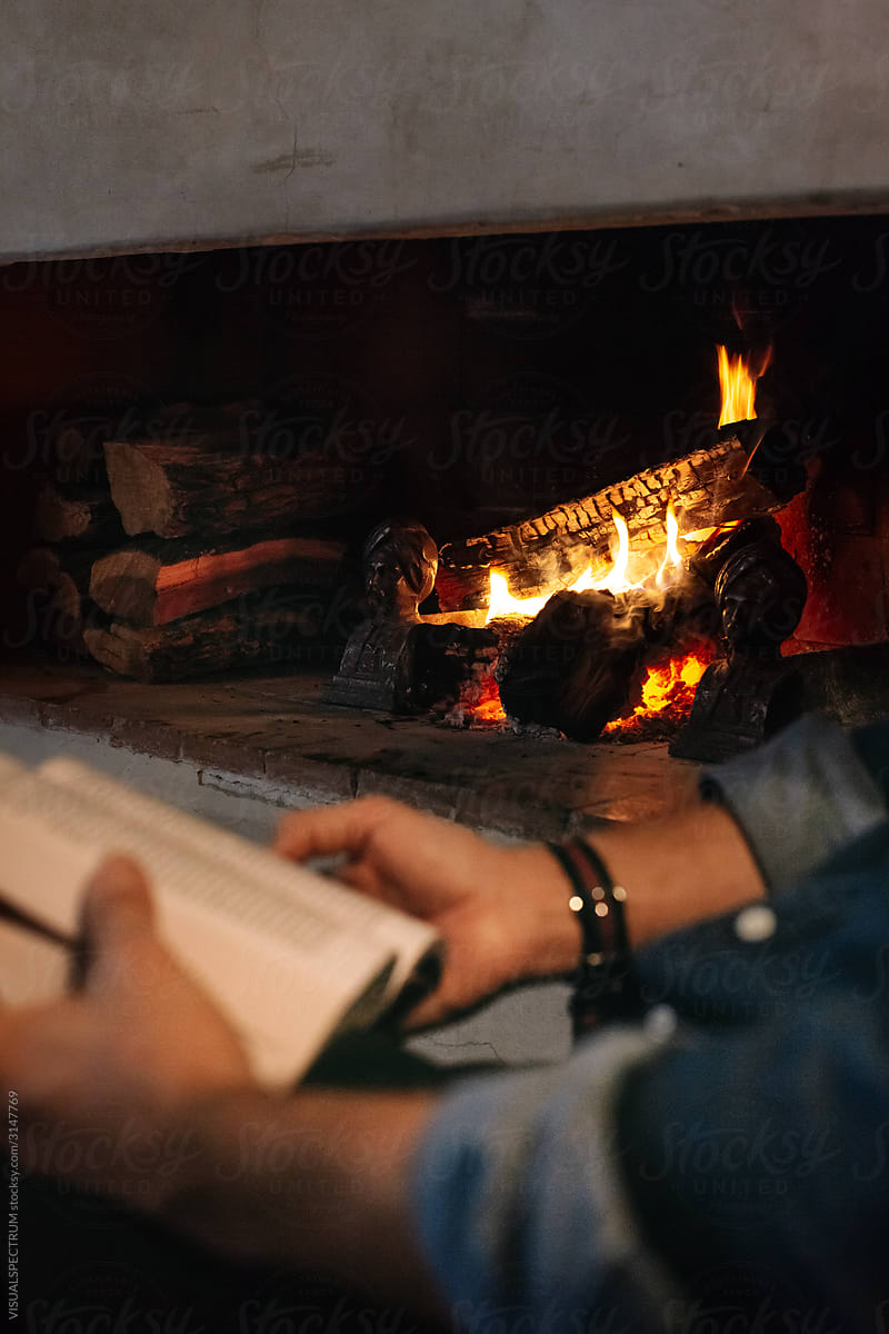 Man Reading Book by Fireplace