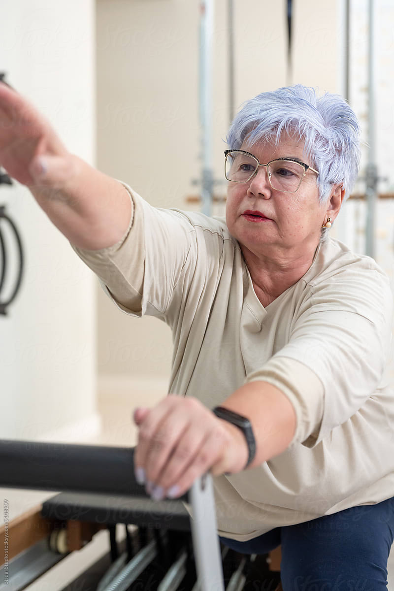 Woman in glasses exercising on Pilates reformer