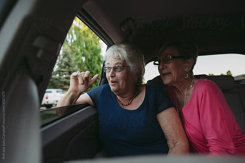 Happy, caucasian seniors having fun in back seat of car